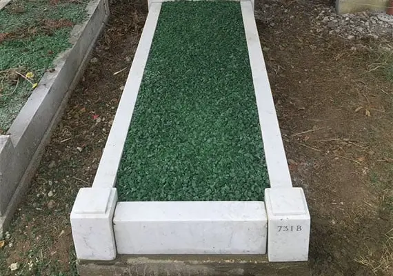 A white marble kerb set with green chippings in a churchyard