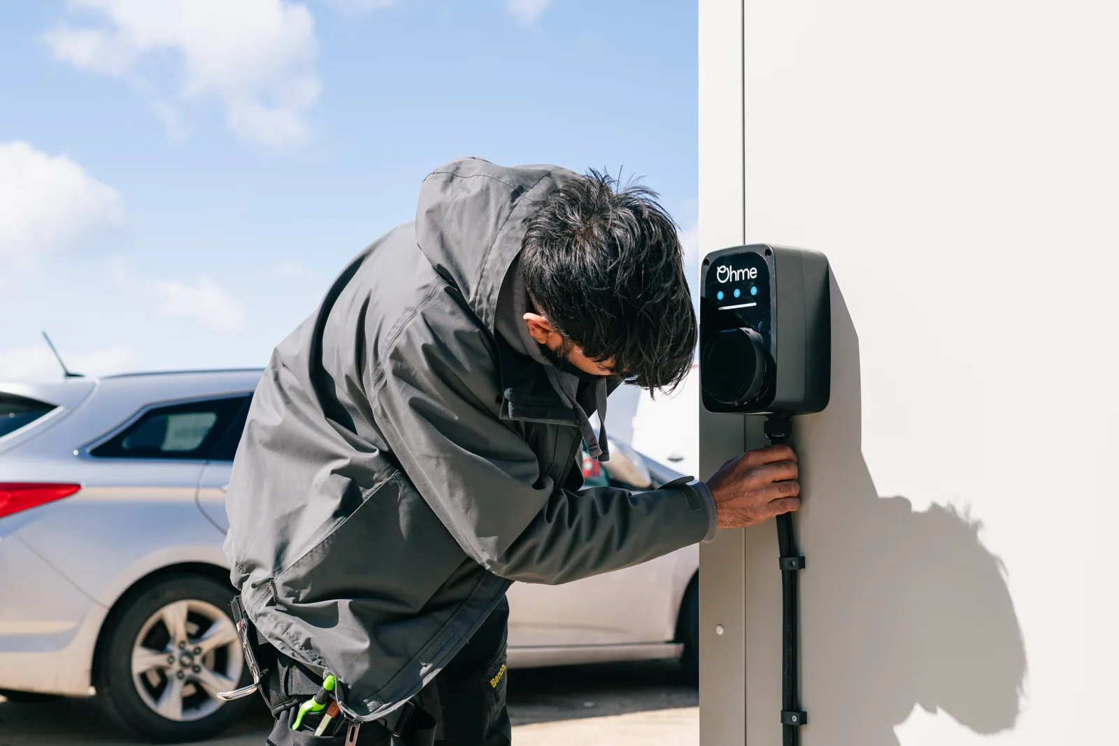 A Plug In Stations engineer fitting an Ohme charger to an outside wall