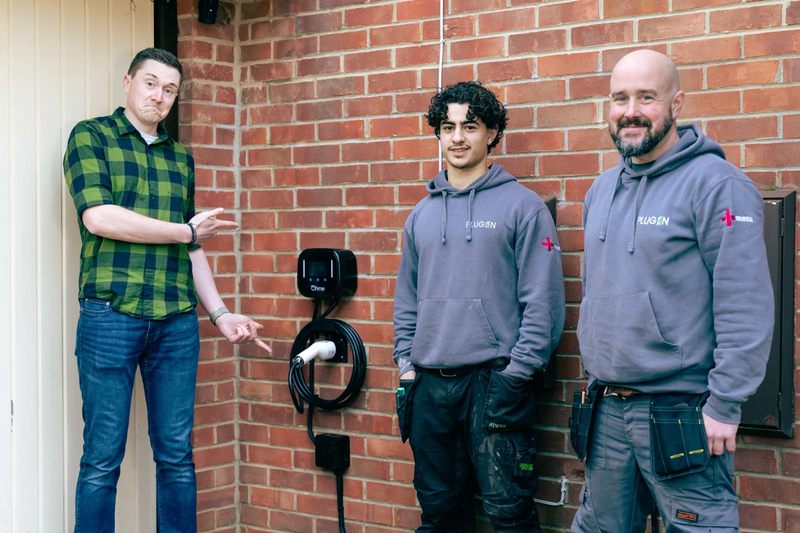 Members of the Plug In Stations team beside a fitted Ohme charger