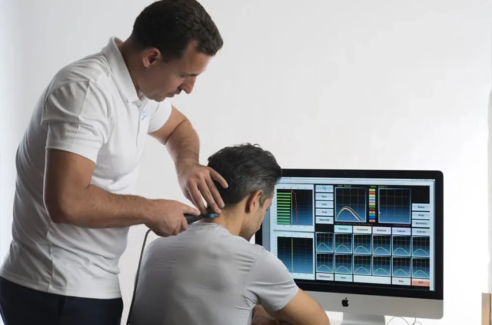 A Proback Victoria chiropractor treating a patient&rsquo;s neck beside a scan on screen