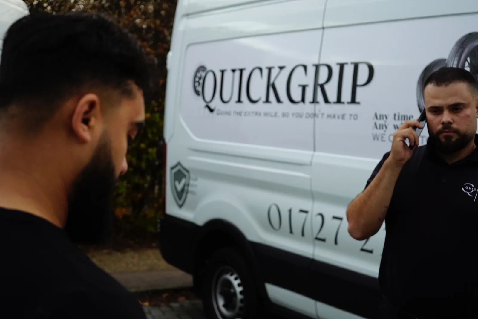 A QuickGrip fitter taking a call beside the van